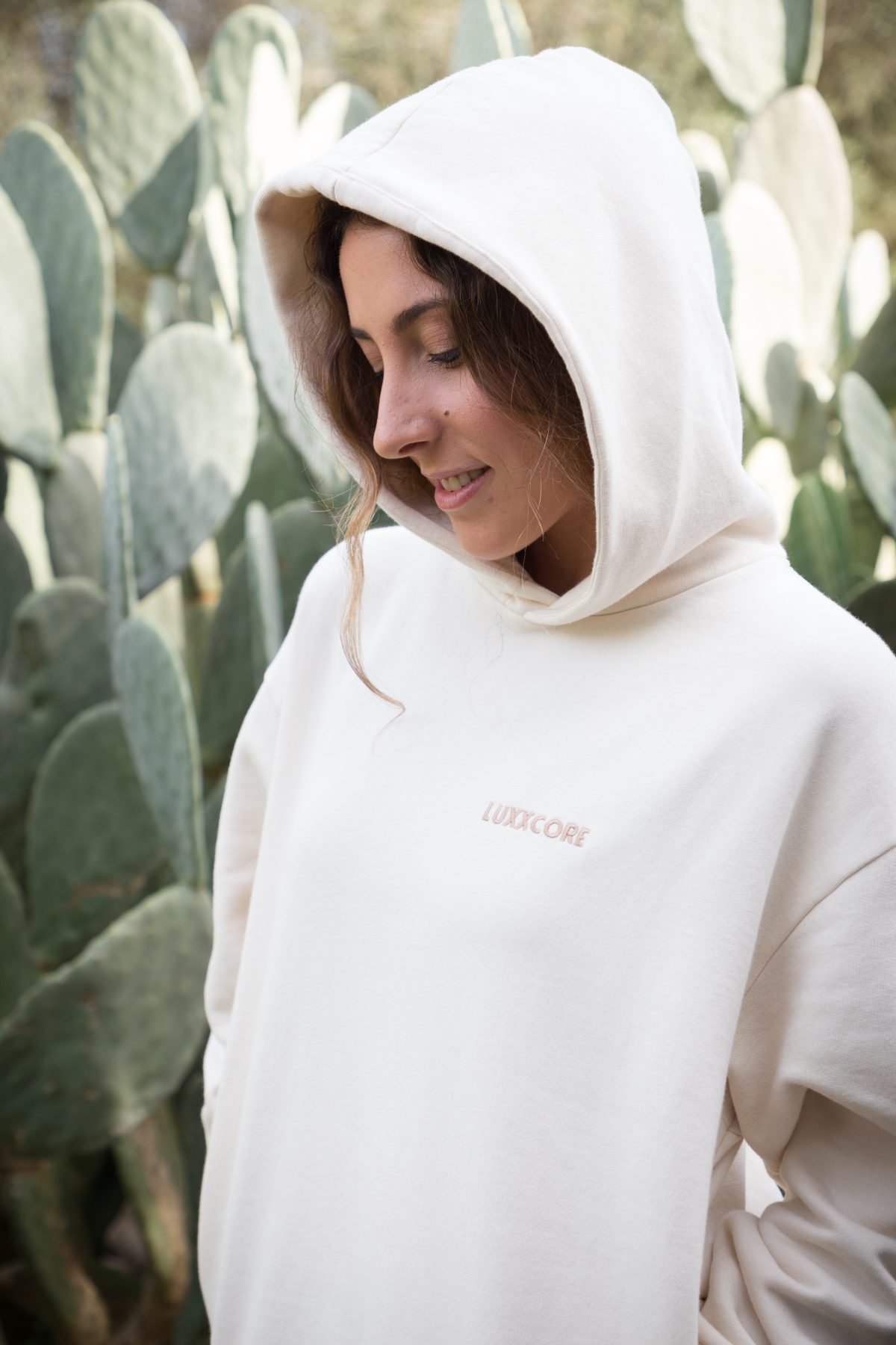 Lucía con sudadera LUXXCORE de algodón orgánico color ecru, en vista tres cuartos, fondo claro.