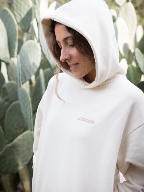 Lucía con sudadera LUXXCORE de algodón orgánico color ecru, en vista tres cuartos, fondo claro.